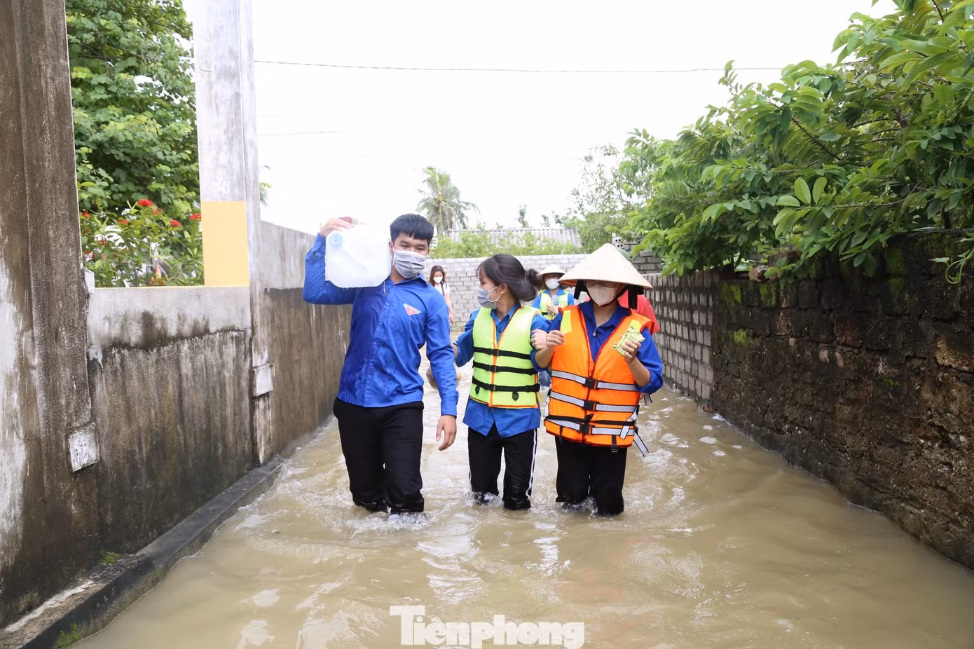 Bạn trẻ lội nước mang lương thực, nước sạch vào tận nhà người dân bị ngập lụt. - Ảnh: Thu Hiền