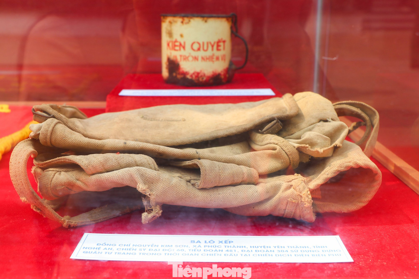 Chiếc ba lô của đồng chí Nguyễn Kim Sơn (xã Phúc Thành, huyện Yên Thành, tỉnh Nghệ An), chiến sĩ Đại đội 60, Tiểu đoàn 481, Đại đoàn 304 sử dụng đựng quân tư trang trong thời gian chiến đấu tại chiến dịch Điện Biên Phủ. Phía trên là chiếc ca uống nước “Kiên quyết làm tròn nhiệm vụ” của Chủ tịch Hồ Chí Minh tặng đồng chí Nguyễn Văn Chính (huyện Nam Đàn, tỉnh Nghệ An), Tiểu đội trưởng thuộc Trung đoàn 98, Đại đoàn 316 vì thành tích xuất sắc trong chiến đấu tại chiến dịch Điện Biên Phủ.