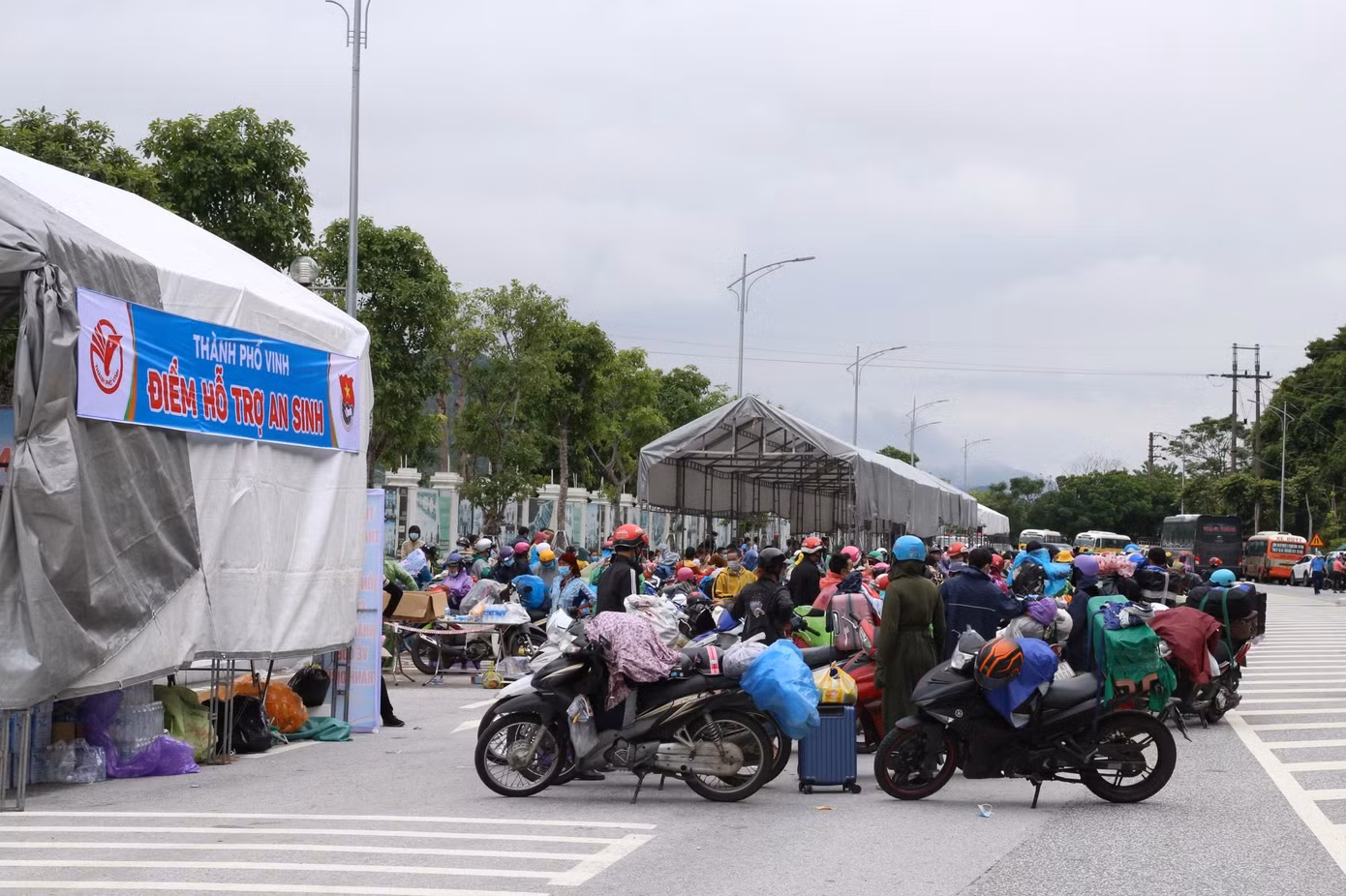 Nhiều người từ các tỉnh thành phía Nam vẫn tiếp tục đổ về chốt kiểm soát cầu Bến Thủy 2. Với mong muốn tiếp sức người dân về quê, Thành đoàn Vinh (Nghệ An) triển khai điểm hỗ trợ an sinh tại đây. Hàng chục đoàn viên thanh niên tích cực tham gia, trong đó có nhiều bạn là học sinh, sinh viên. (Ảnh: Thu Hiền)