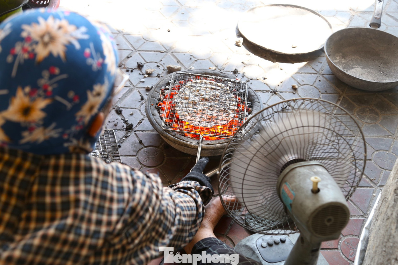 Sức nóng từ chậu than đỏ rực buộc người nướng bánh phải trang bị bảo hộ cho phần mặt, tay, đầu gối và ống chân. Những chiếc quạt điện chạy hết công suất cũng chỉ giúp họ xua bớt đôi chút cái nóng ngột ngạt.