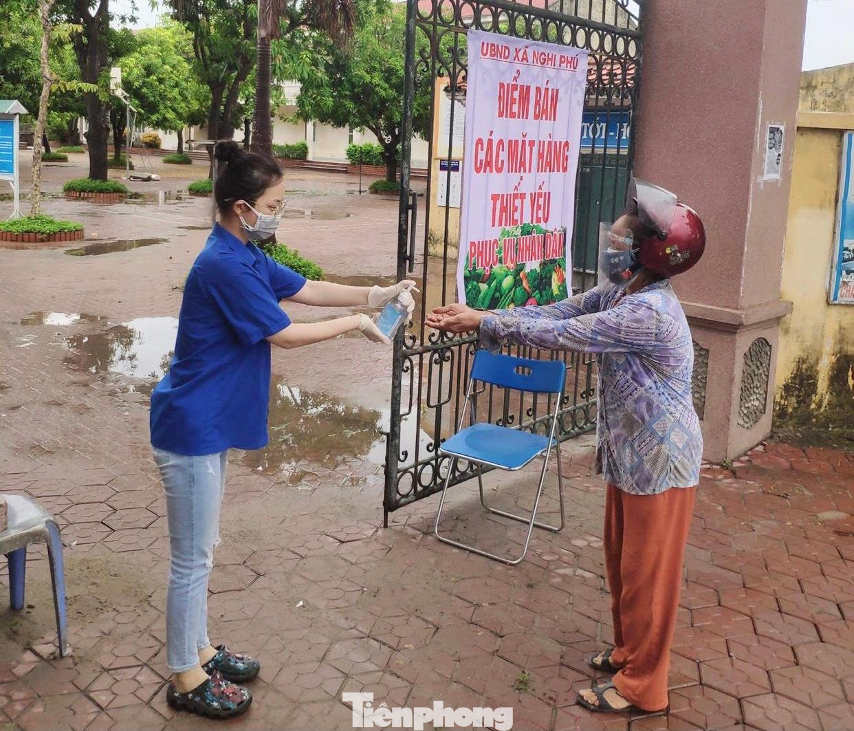Lực lượng đoàn viên thanh niên xã Nghi Phú đã có mặt từ sáng sớm để hỗ trợ đo thân nhiệt, rửa tay sát khuẩn và kiểm tra giấy đi chợ của người dân.