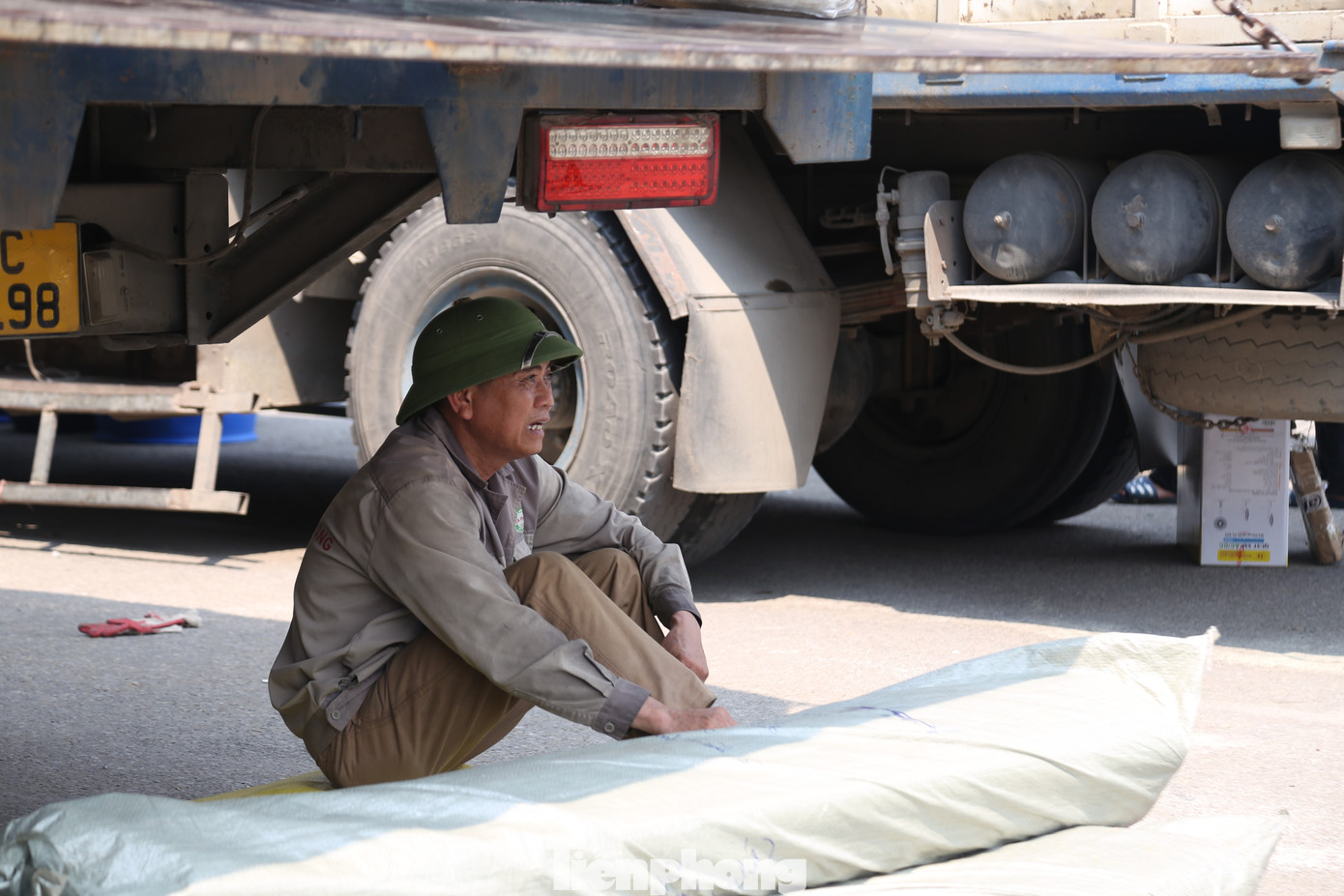 Tranh thủ khi chưa có hàng để bốc, người cửu vạn nương theo bóng râm của thùng xe ngồi nghỉ.