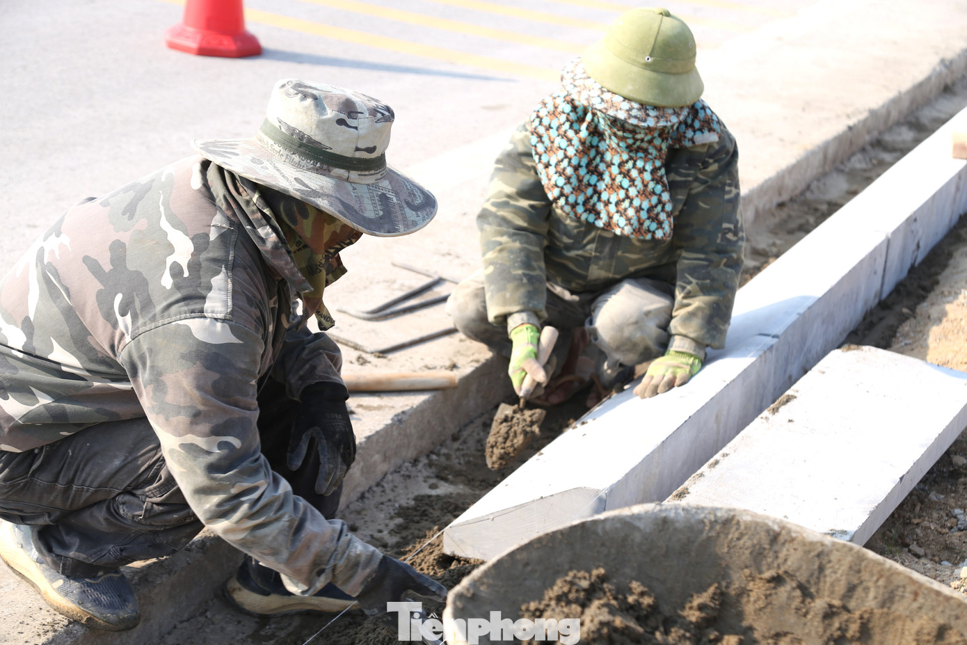 Trang bị 3 lớp áo, 1 mũ trùm đầu kín mít nhưng anh Lương Văn Tuấn (46 tuổi, trú huyện Tương Dương, Nghệ An, bên trái) vẫn cảm nhận rõ sự bỏng rát khi thi công trên vỉa hè không một bóng cây xanh. “Nắng xiên thẳng vào người. Hơi nóng từ mặt đường nhựa hắt lên hầm hập. Công việc vốn đã nặng nhọc nay càng vất vả hơn”, anh Tuấn chia sẻ.