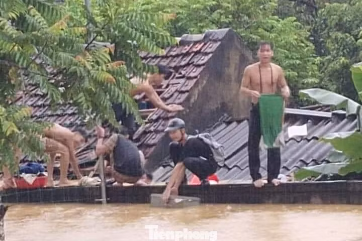 Các em học sinh đội mưa chờ lực lượng chức năng ứng cứu.