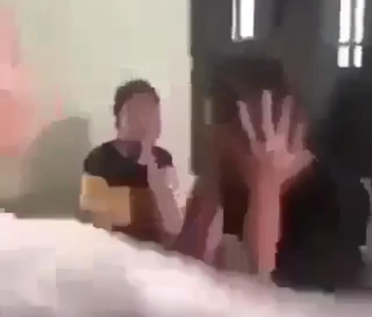 Hình ảnh nữ sinh bị đánh chỉ dám ôm mặt chịu trận, phía sau có người chứng kiến nhưng không can ngăn