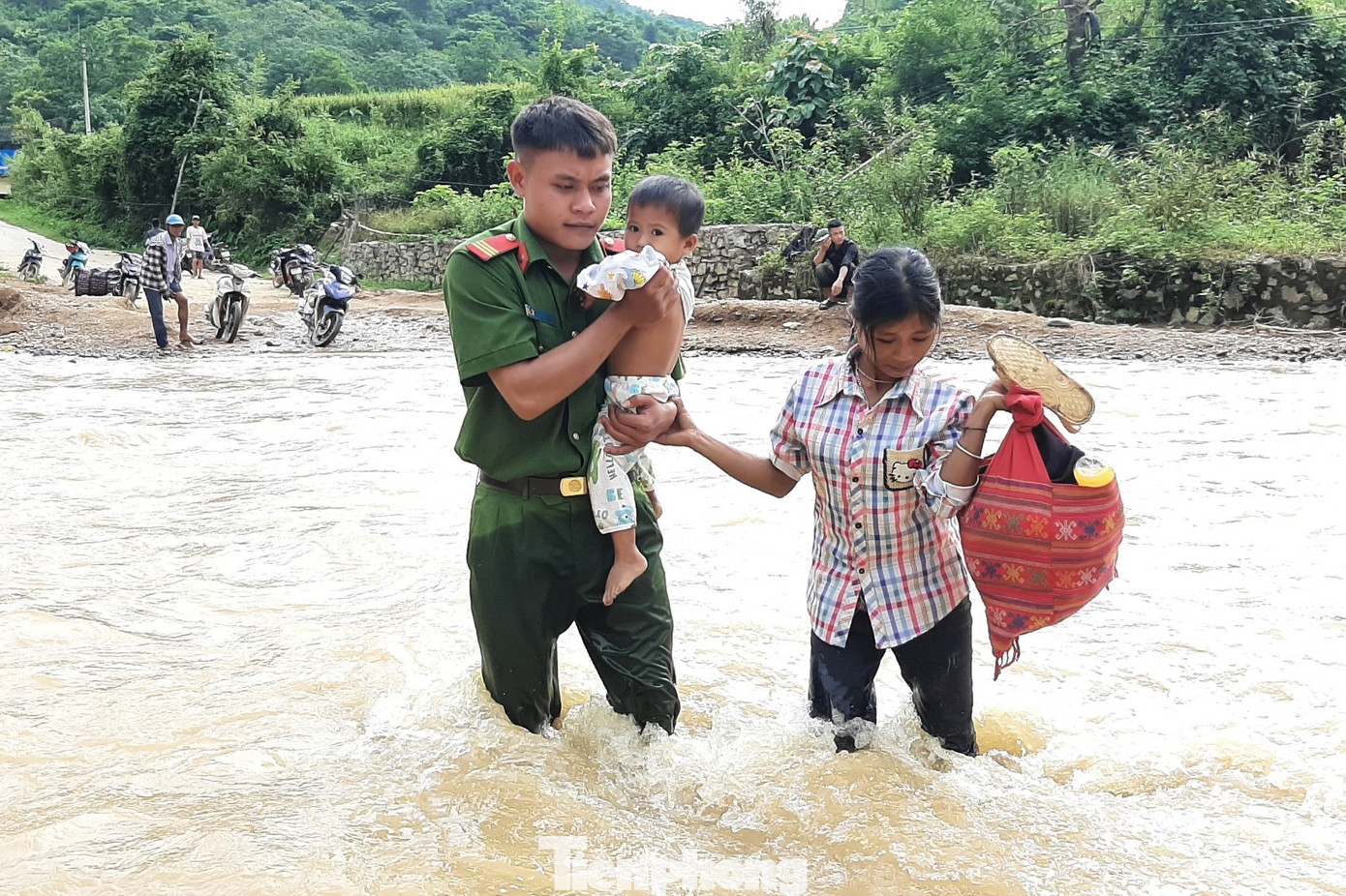 Chiến sĩ công an hỗ trợ người dân di chuyển qua dòng nước chảy xiết.
