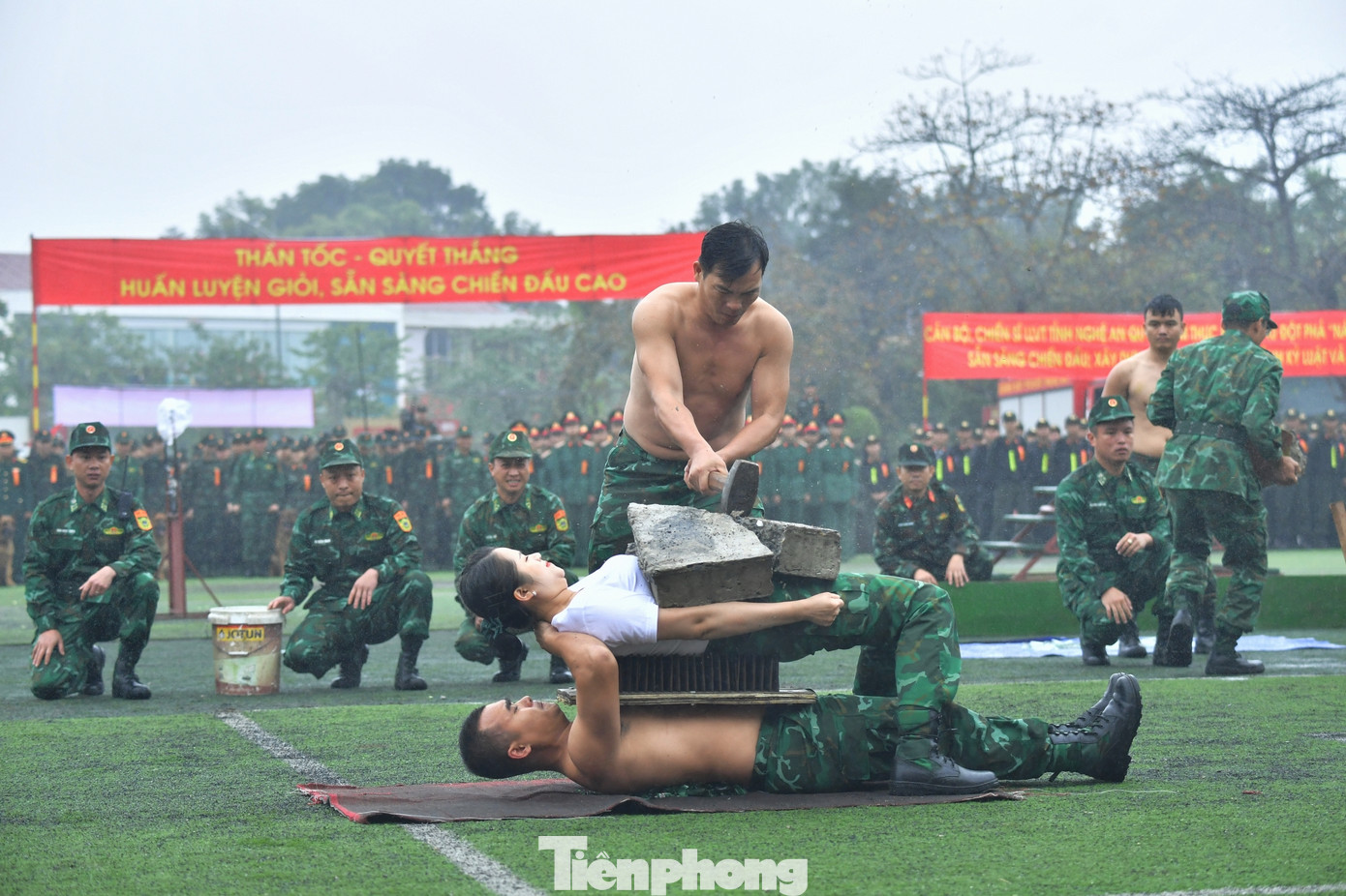 Hai cán bộ Biên phòng nằm trên thủy tinh vỡ, trên bàn chông để đồng đội dùng búa tạ đập vỡ tảng đá trên người.