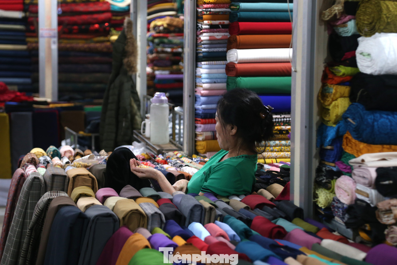 Một tiểu thương bán vải ở chợ Vinh vừa ngồi ngóng khách vừa ăn bỏng ngô.