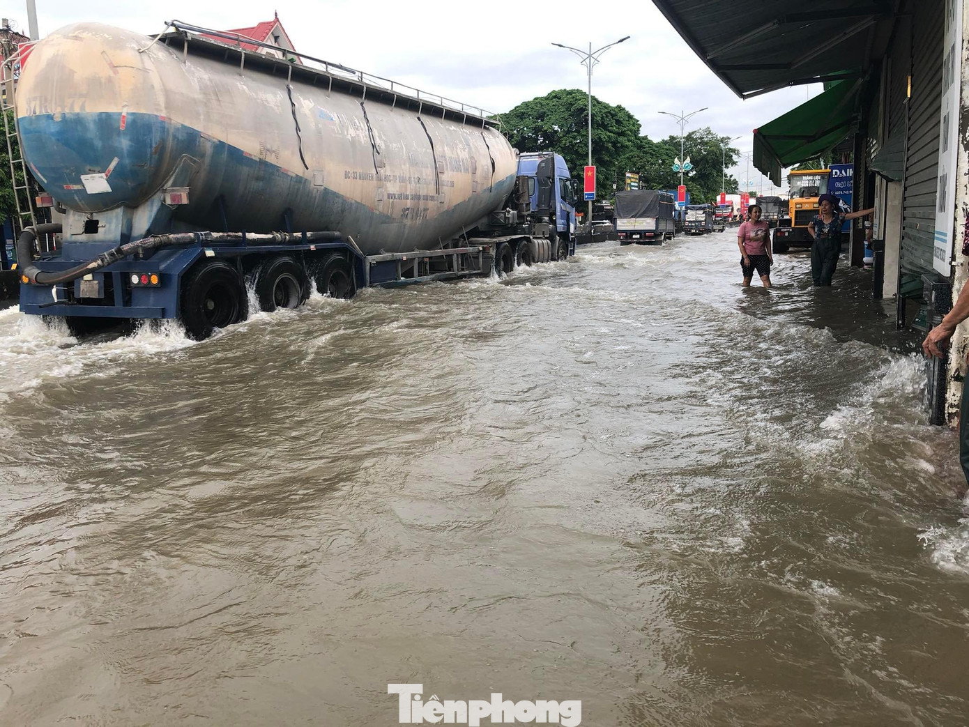 Do nước ngập sâu, các phương tiện phải di chuyển chậm để hạn chế việc xe chạy tạo thành sóng tràn vào nhà dân.