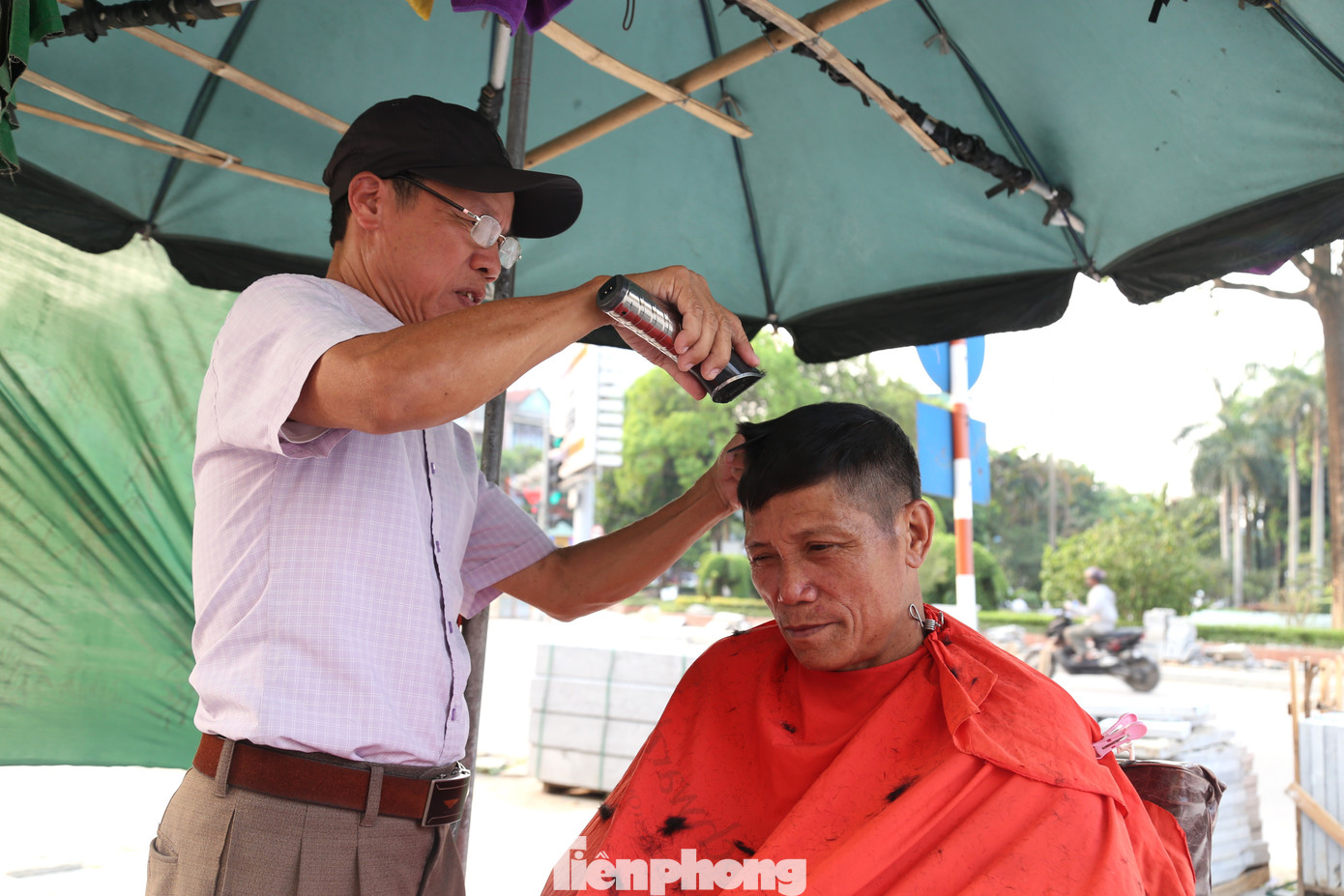 Nắng nóng, chủ "tiệm" cắt tóc phải dùng ô, tấm vải che chắn.