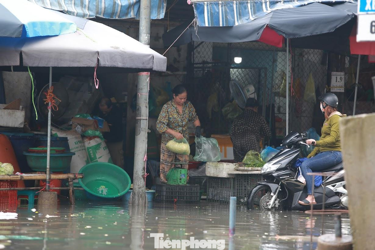 Nước lũ bủa vây, một số tiểu thương bì bõm trong nước bán hàng