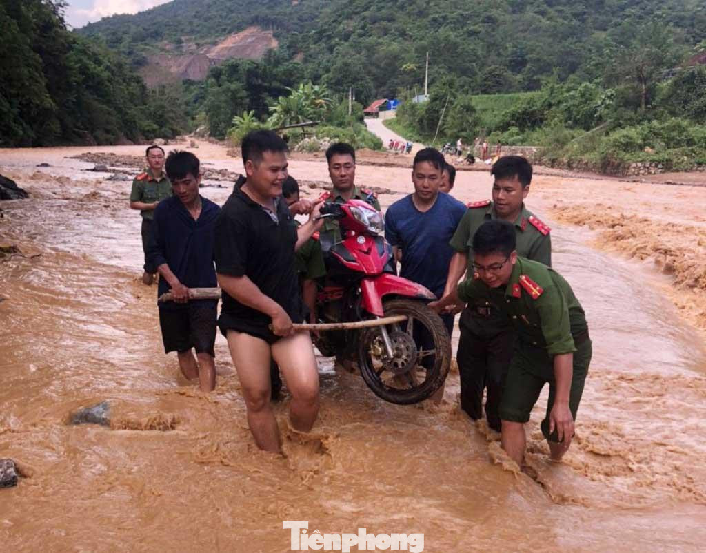 Hỗ trợ người dân khiêng xe máy qua dòng nước chảy xiết