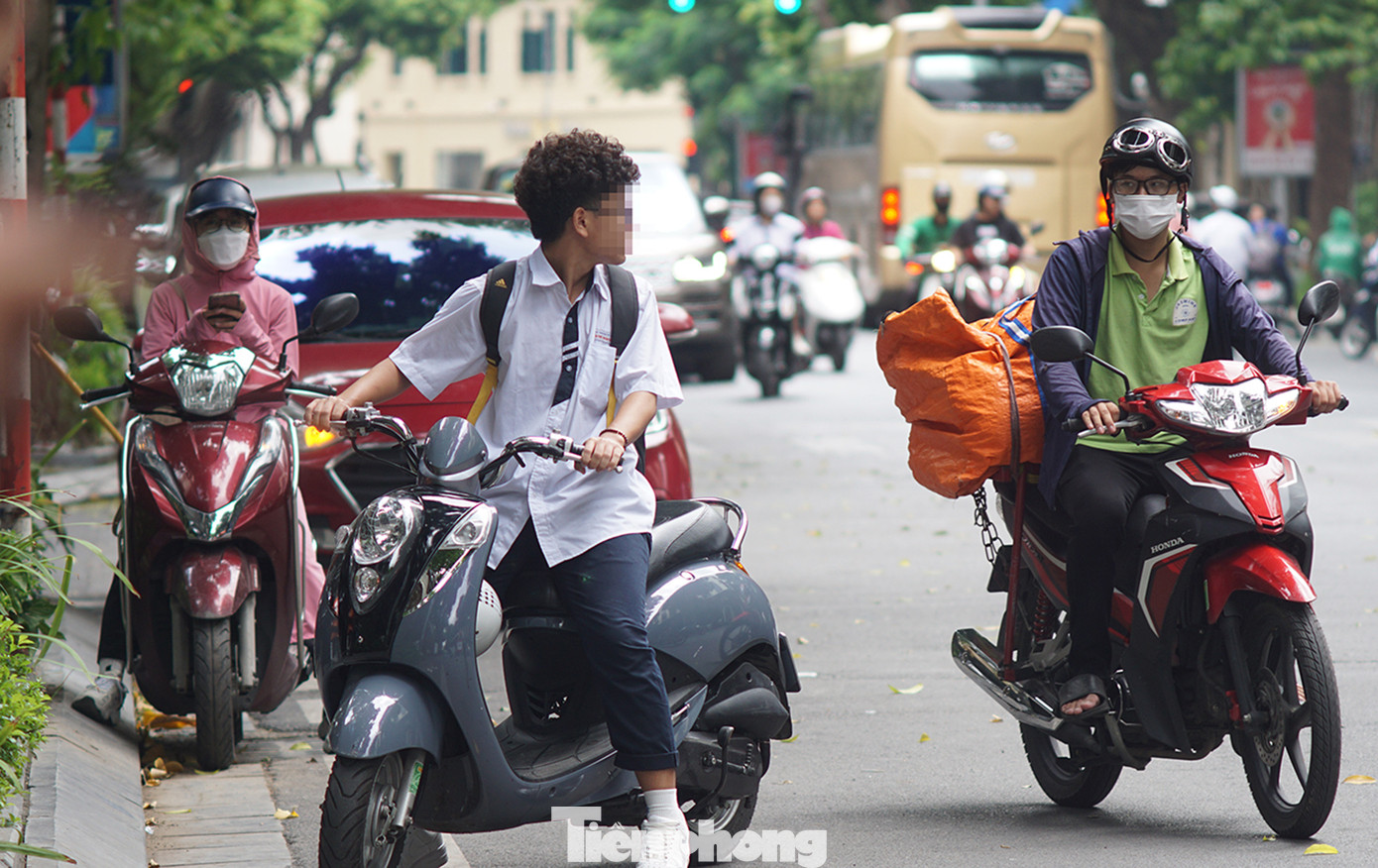 Một em học sinh điều khiển xe gắn máy không đội mũ bảo hiểm trên phố Hai Bà Trưng.