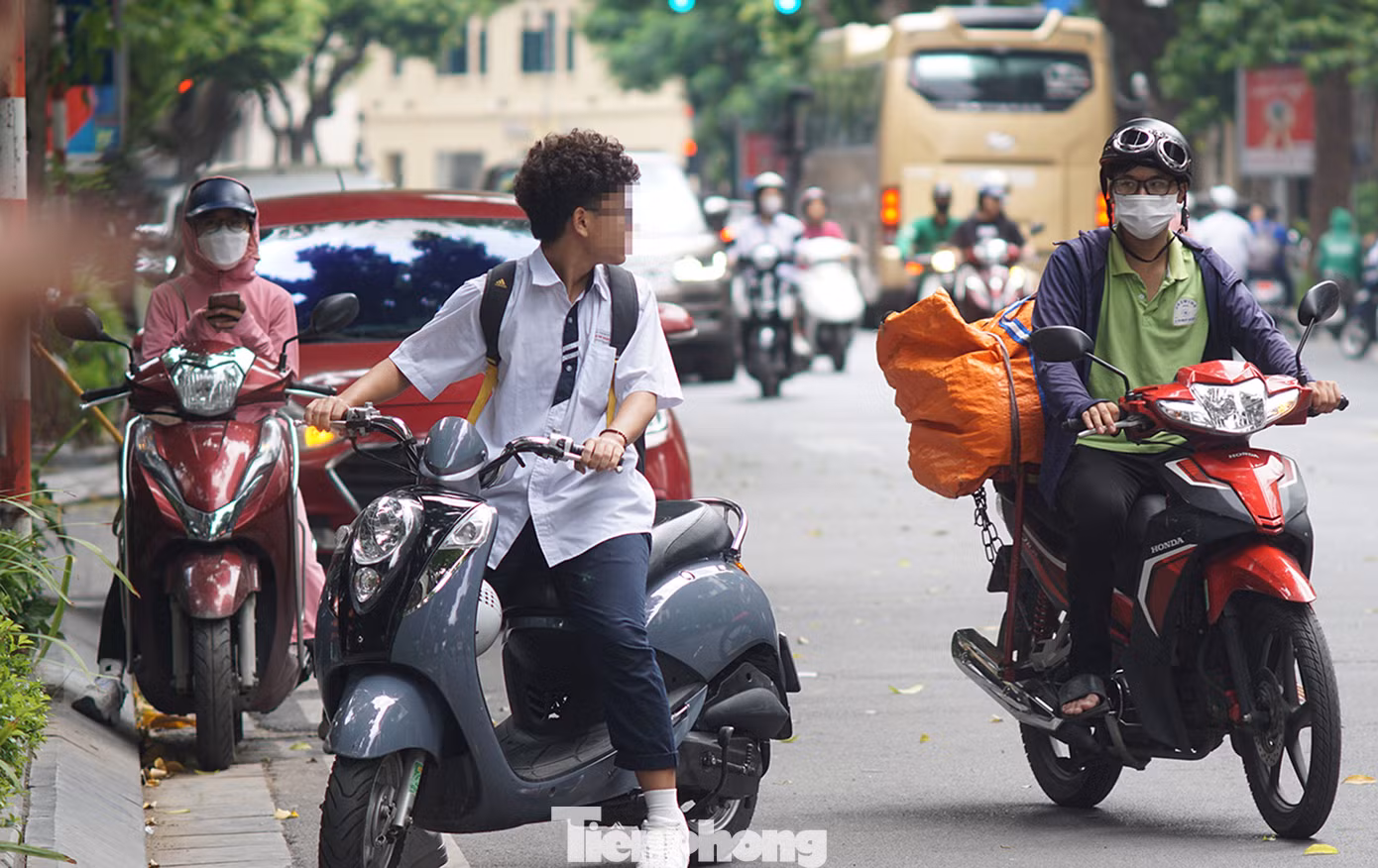 Một em học sinh điều khiển xe gắn máy không đội mũ bảo hiểm trên phố Hai Bà Trưng.