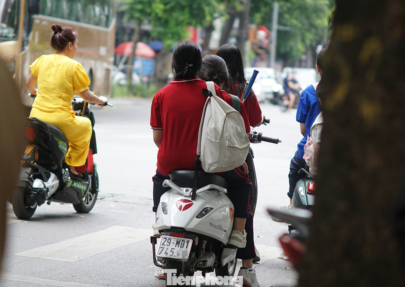 Xe máy điện chở theo 3 học sinh không đội mũ bảo hiểm.