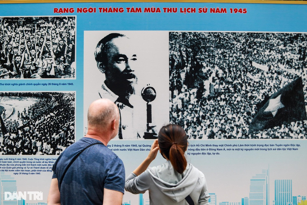 Người phụ nữ Việt đang dịch, truyền tải lại nội dung chú thích ảnh cho vị khách nước ngoài (Ảnh: Tâm Linh).