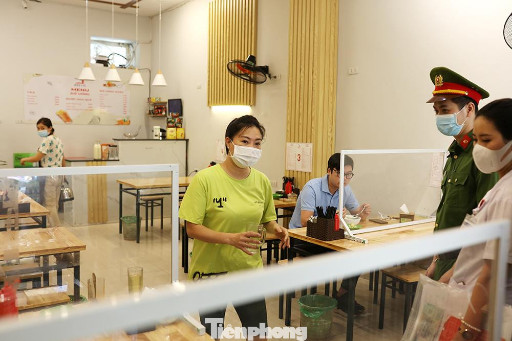 Các hàng quán ăn trước cổng bệnh viện Việt Đức được cán bộ y tế và công an phường nhắc nhở thực hiện tấm chắn vách ngăn phục vụ người dân đến ăn uống.