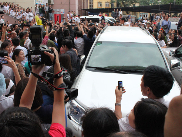Hàng trăm người bao quanh chiếc ô tô đưa cháu bé về Bệnh viện. Ảnh: L.G