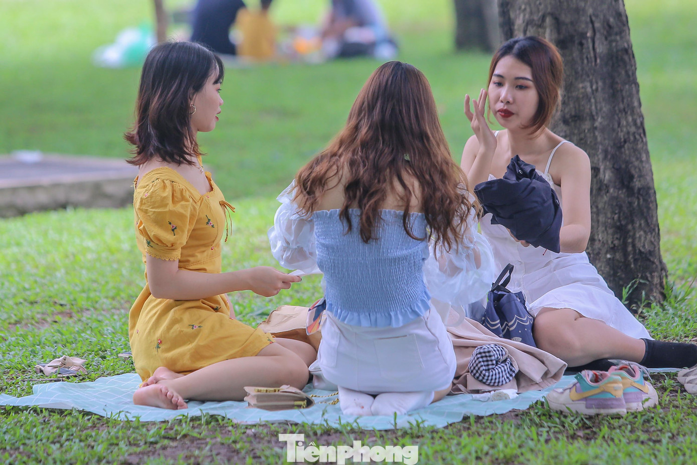 Các bạn nữ tự nhiên thả dáng bên bãi cỏ mà không đeo khẩu trang.