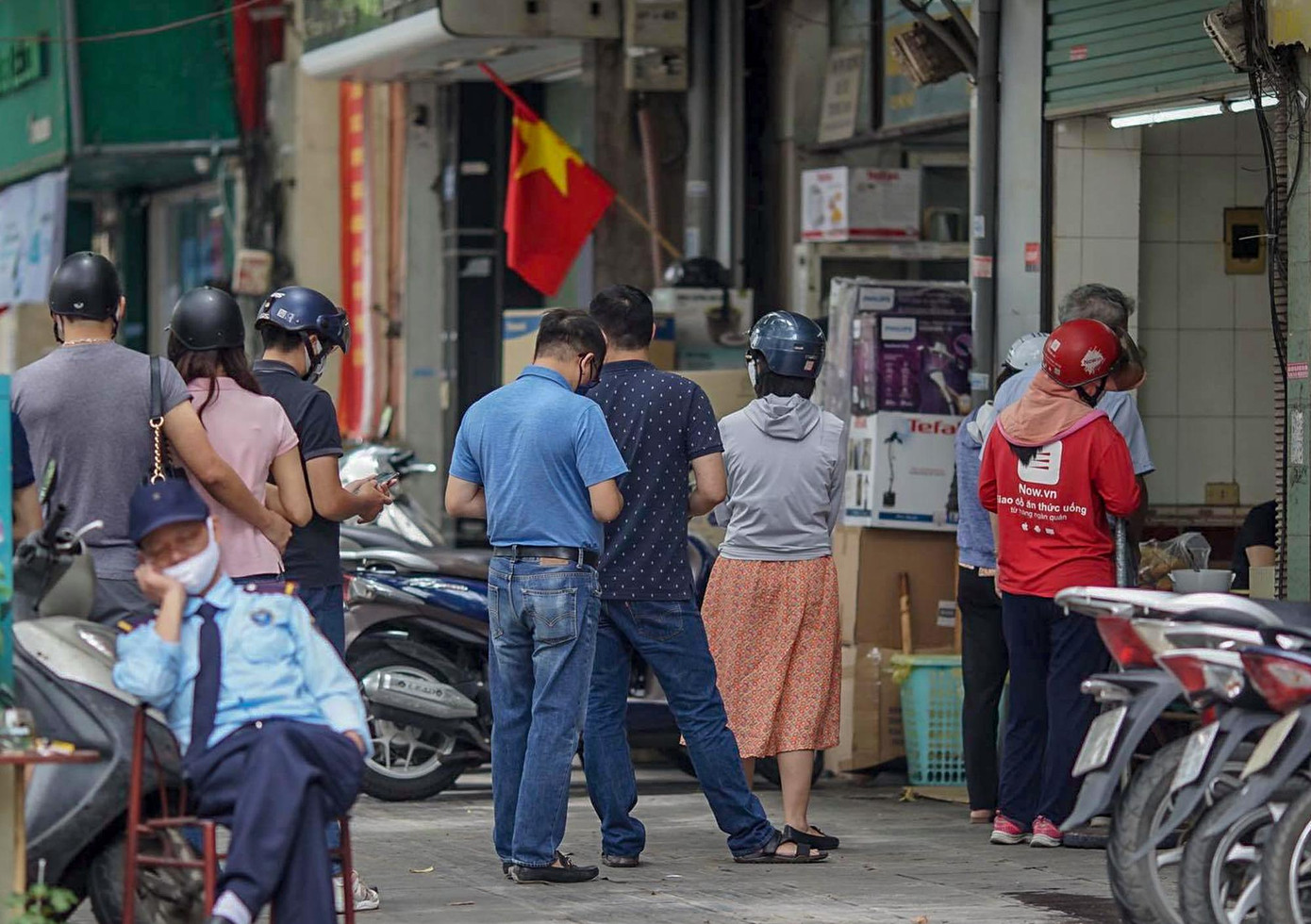 Một số hàng quán chuyển sang bán hàng mang về. Trong ảnh: Nhiều người xếp hàng mua bánh mì tại một cửa hàng trên khu phố cổ sau 12h hôm nay.