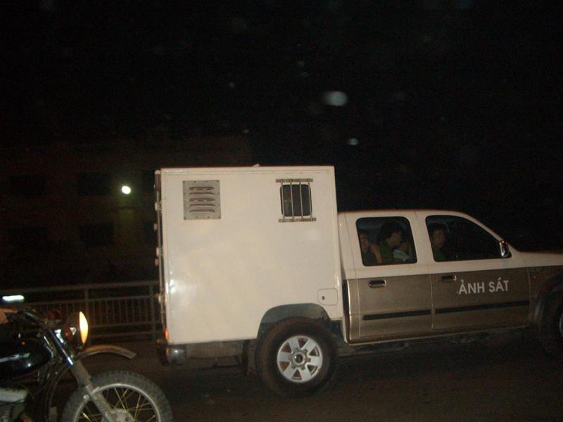 Ông Tiến ngồi phía sau thùng xe chở phạm nhân, phía trước trong cabin là 4 chiến sĩ công an áp giải. Ảnh chụp trên cầu Chương Dương. Ảnh: Phạm Tuyên.