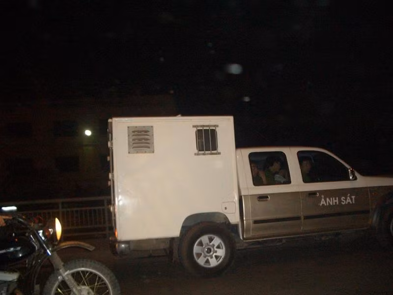 Ông Tiến ngồi phía sau thùng xe chở phạm nhân, phía trước trong cabin là 4 chiến sĩ công an áp giải. Ảnh chụp trên cầu Chương Dương. Ảnh: Phạm Tuyên. Ông Tiến ngồi phía sau thùng xe chở phạm nhân, phía trước trong cabin là 4 chiến sĩ công an áp giải. Ảnh chụp trên cầu Chương Dương. Ảnh: Phạm Tuyên.