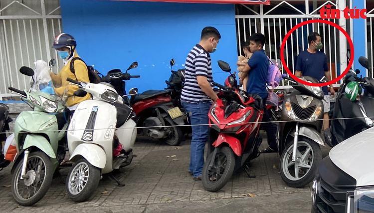 Hai người đàn ông đứng ra trông, giữ xe máy rồi thu tiền các phụ huynh.