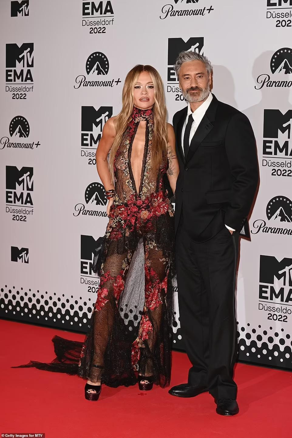 Rita Ora sánh đôi cùng bạn trai hơn 15 tuổi, đạo diễn Taika Waititi. Trở lại với vai trò MC của MTV EMA sau 5 năm, nữ ca sĩ 50 sắc thái chọn cho mình chiếc váy ren đỏ - đen đầy khiêu khích. Ảnh: Getty Images.
