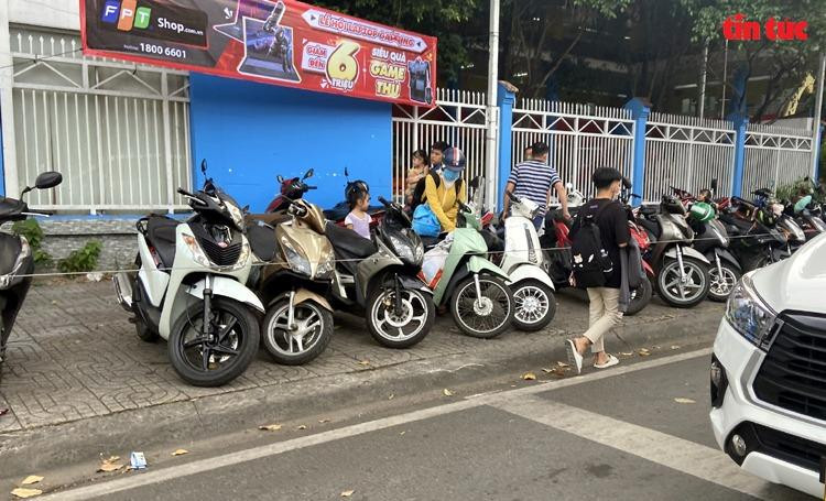 Vỉa hè trước cổng Trường mầm non Vàng Anh trên đường Nguyễn Trãi (Phường 2, Quận 5) được "quây" lại để giữ xe có thu tiền, đẩy người đi bộ xuống lòng đường.