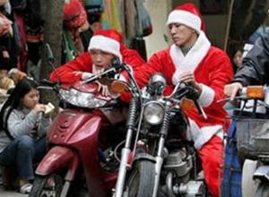 Ông già Noel đi phát quà đang chờ đèn giao thông trên đường phố Hà Nội. Ảnh: AP.