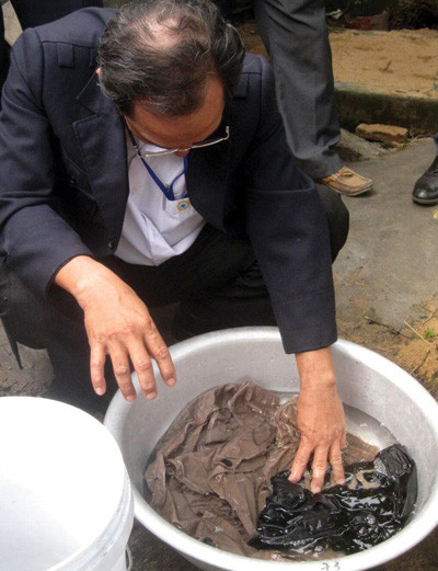 Đoàn công tác ngâm bộ quần áo bà Phụng mua vào thau nước để tìm sinh vật lạ còn sót lại. Ảnh: Đức Huy. Đoàn công tác ngâm bộ quần áo bà Phụng mua vào thau nước để tìm sinh vật lạ còn sót lại. Ảnh: Đức Huy