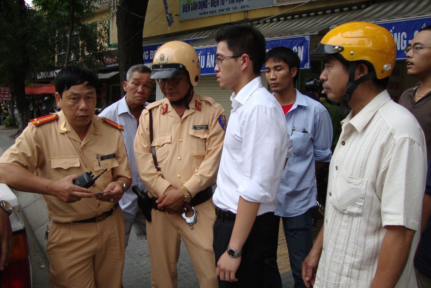 Người điều khiển xe máy đội mũ bảo hiểm màu vàng, người điều khiển ô tô mặc áo trăng làm việc với cơ quan chức năng tại hiện trường
