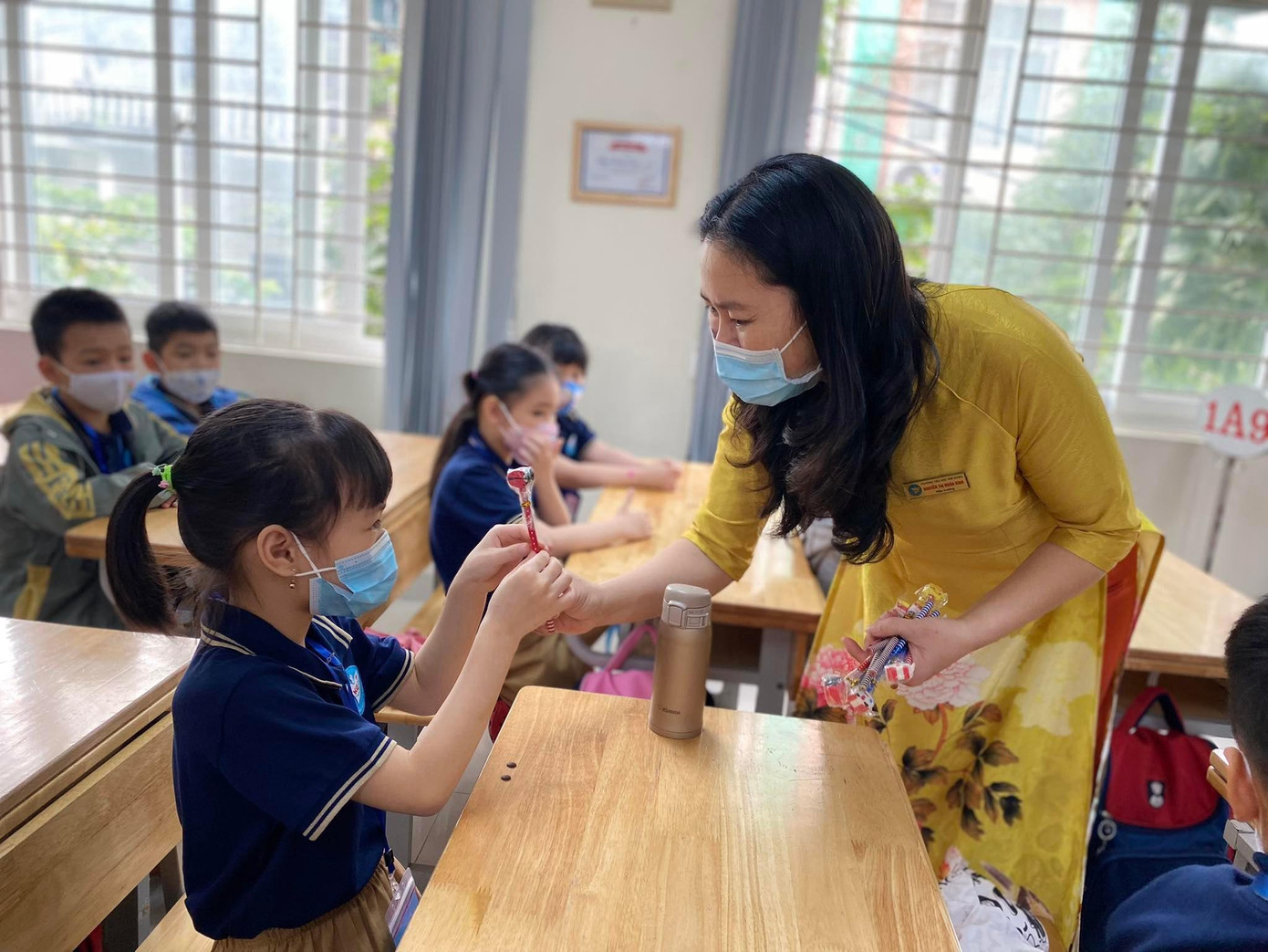 Cô giáo Nguyễn Thị Ngân Bình, Hiệu trưởng Trường tiểu học Kim Giang, quận Thanh Xuân hôm nay cũng mặc chiếc áo dài thật đẹp tặng quà cho từng học sinh lớp 1.