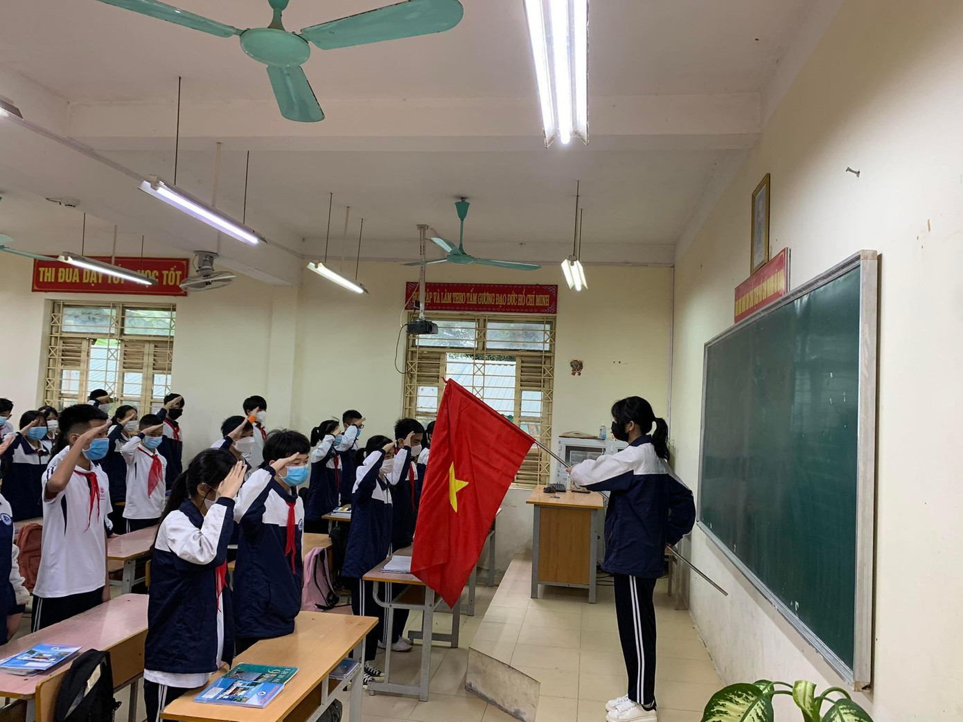 Học sinh chào cờ trong lớp học.