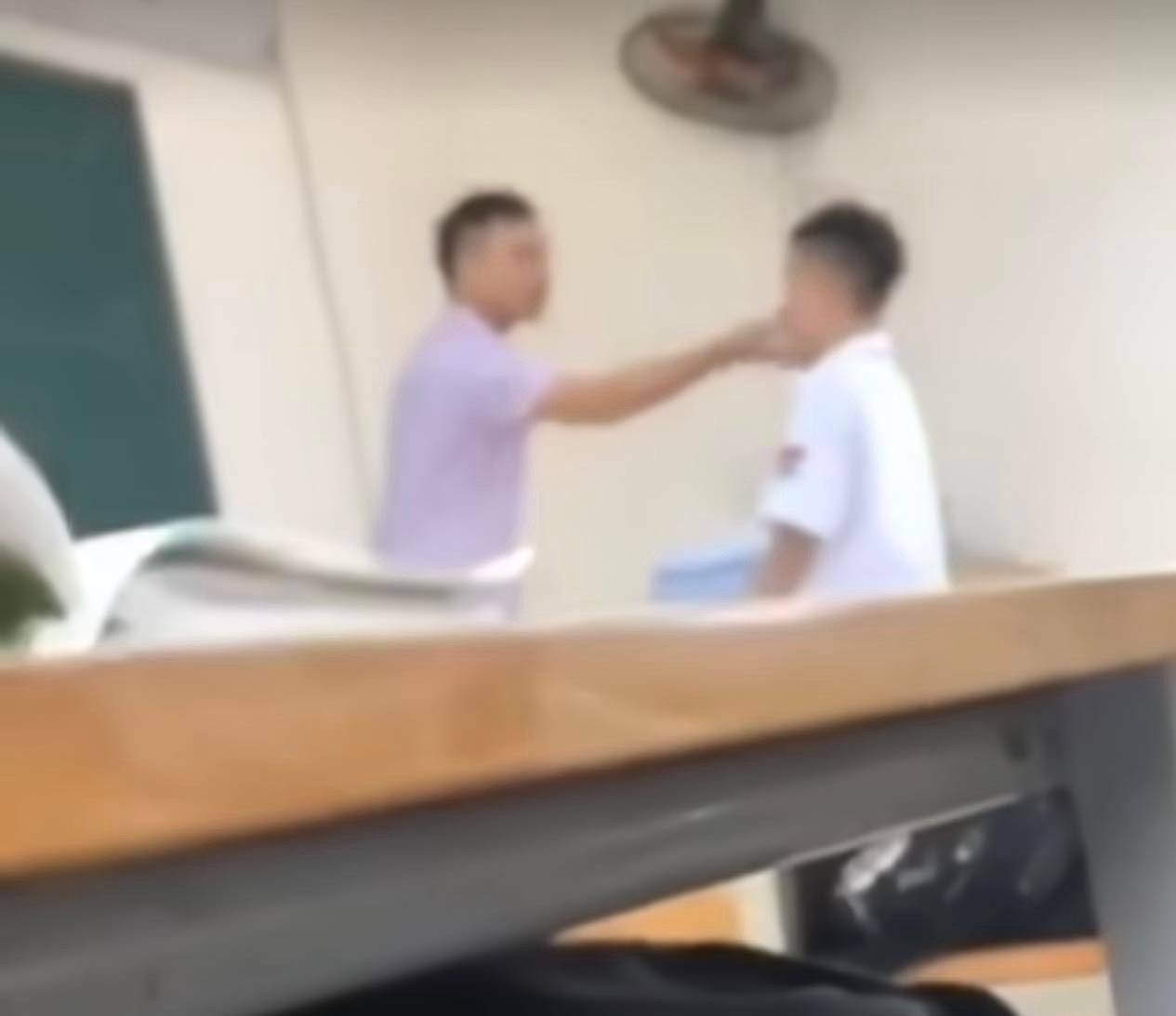 Thầy giáo đứng trên bục giảng có hành động chỉ tay vào mặt, túm cằm và xưng “mày – tao” với học sinh. (ảnh cắt từ video) Thầy giáo đứng trên bục giảng có hành động chỉ tay vào mặt, túm cằm và xưng “mày – tao” với học sinh. (ảnh cắt từ video)