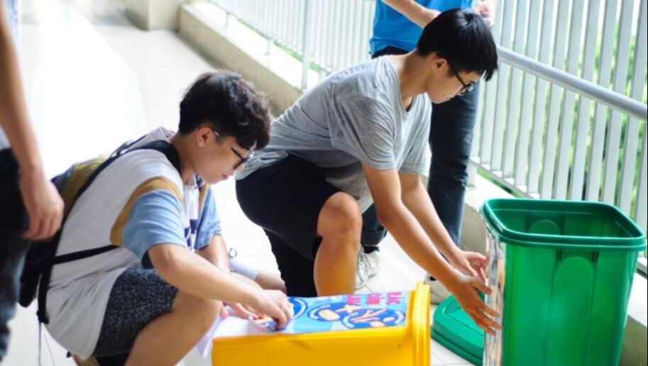 Học sinh tại trường THCS Nghĩa Tân dán nhãn cho thùng rác để phân loại rác trong trường học. Ảnh: Vert Xanh.