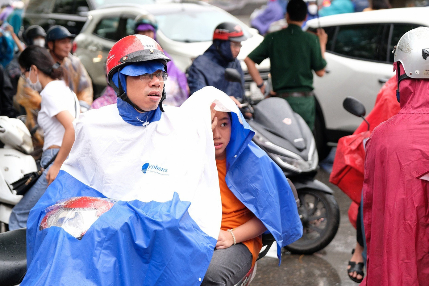 Cha và con "đội mưa" đến điểm thi dự kỳ thi nóng nhất trong đợt tuyển sinh lớp 6 của Hà Nội.