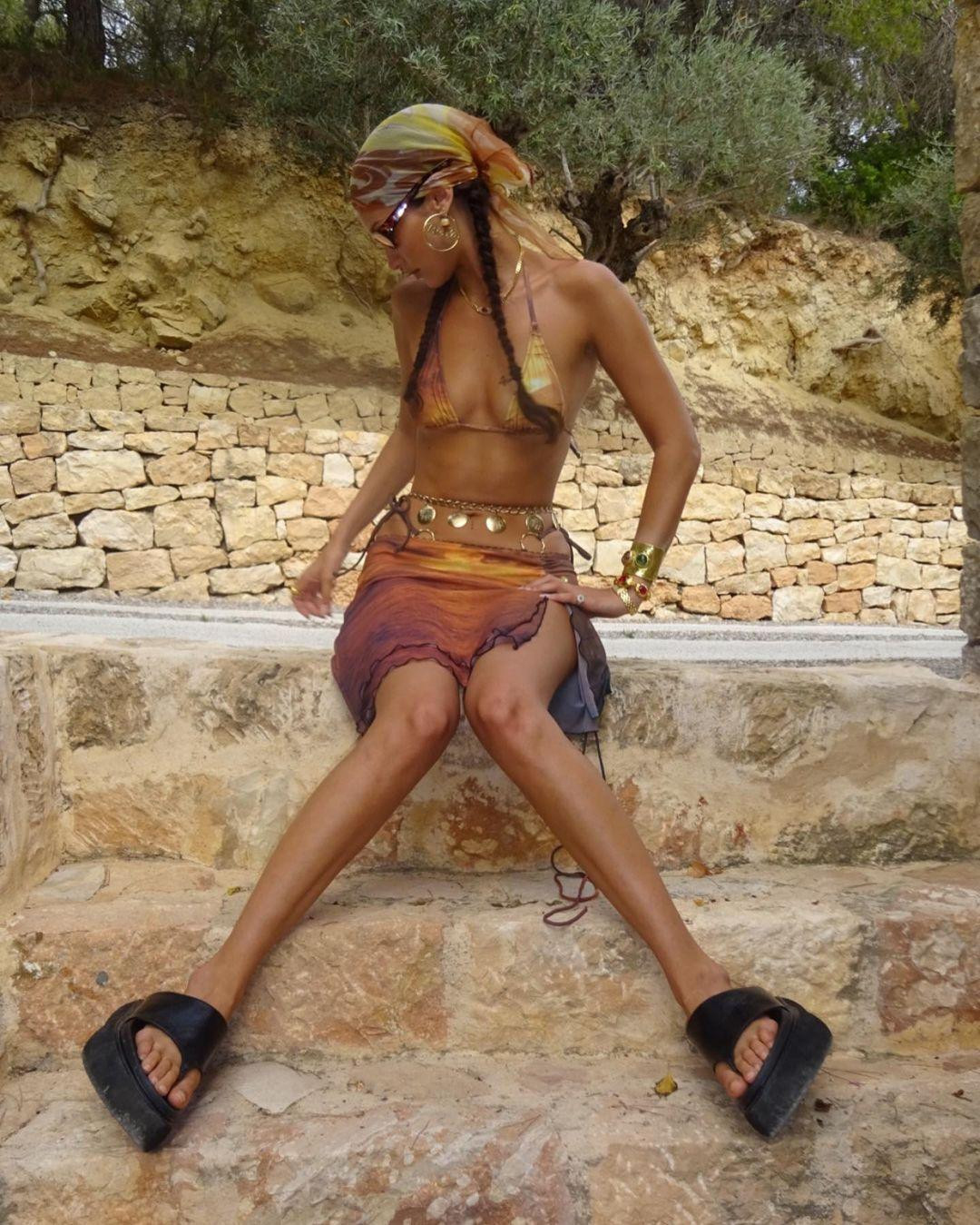 Bella Hadid vừa chia sẻ loạt ảnh "thả dáng" với bikini trên Instagram. Trong ảnh, người đẹp sinh năm 1996 mặc đồ bơi hai mảnh màu cam-vàng bé xíu, đội khăn trùm đầu, đi dép xỏ ngón đế bánh mì, mắt kính màu và đeo rất nhiều trang sức.