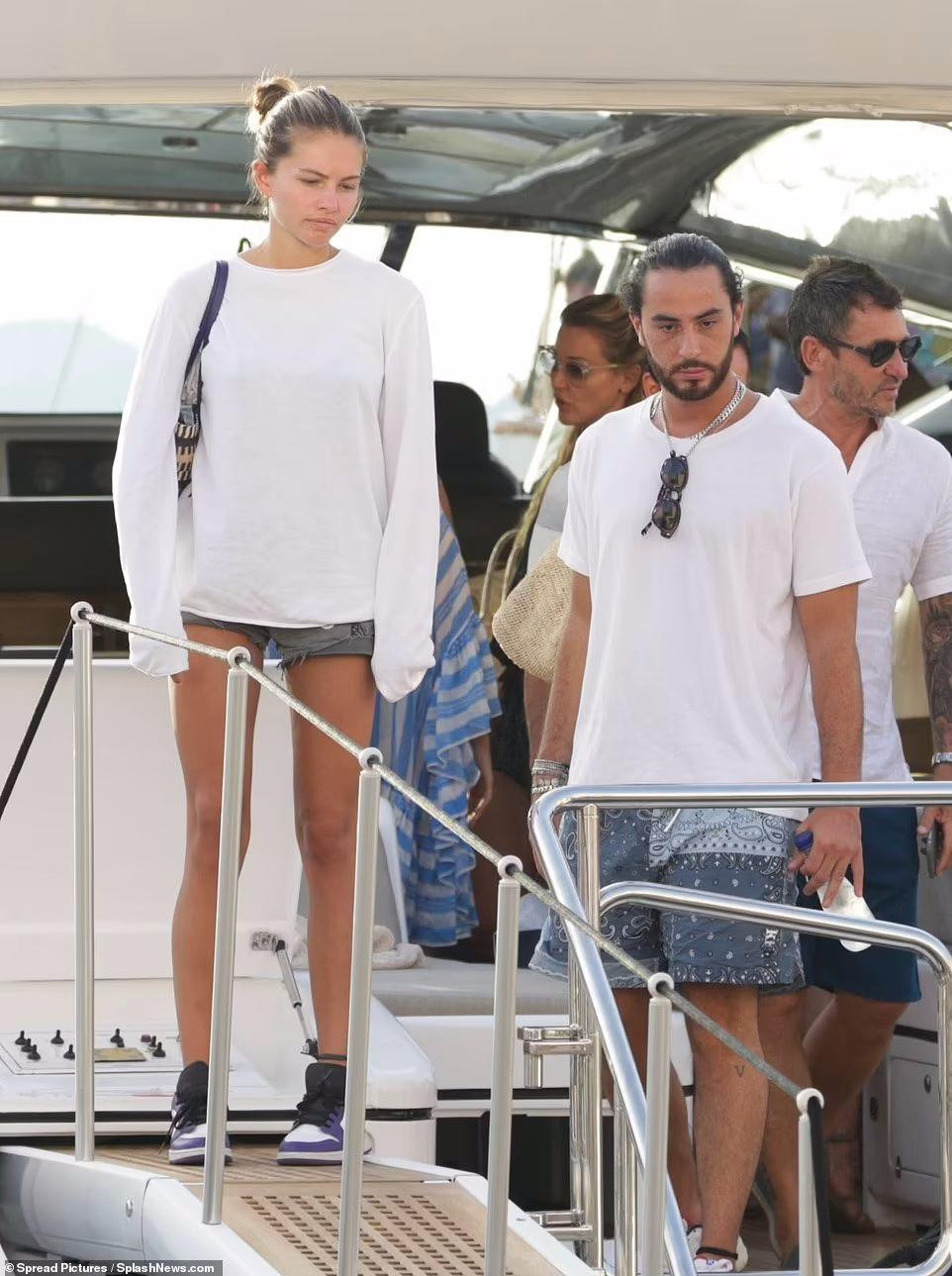 Sau khi rời du thuyền, người đẹp Gen Z mặc thêm áo trắng dài tay, đi giày thể thao và dùng túi kẹp nách. Chiếc quần đùi giúp cô khoe được đôi chân thon dài. Được biết, cô cao 1m70.