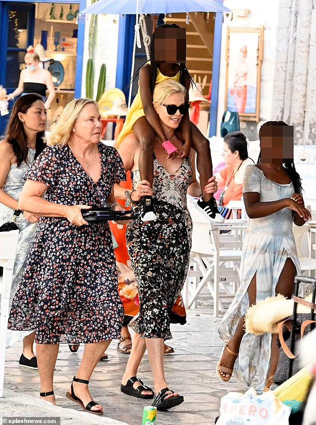 Người đẹp thoải mái cõng cổ con gái August. Có thể thấy, sau khi nhận nuôi hai con gái, Charlize đóng vai trò vừa là mẹ vừa là cha.