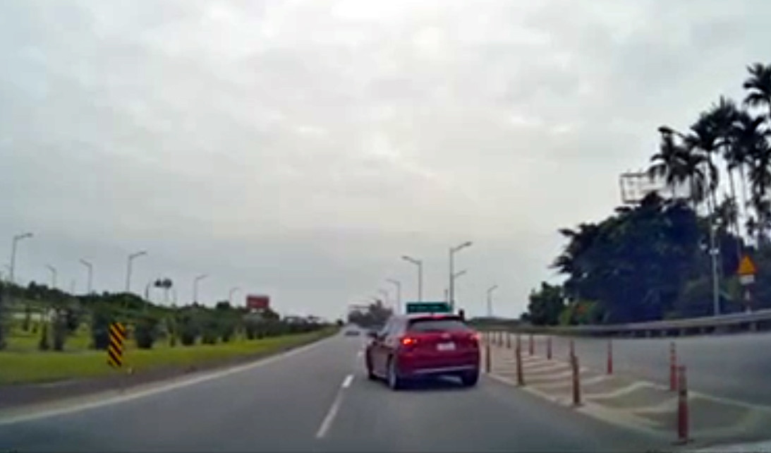 Hình ảnh ô tô màu đỏ đi lùi trên cao tốc.