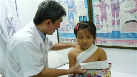 Bác sĩ Lĩnh đang băng cố định xương cho bé Anh - Ảnh: Vietnamnet.vn.