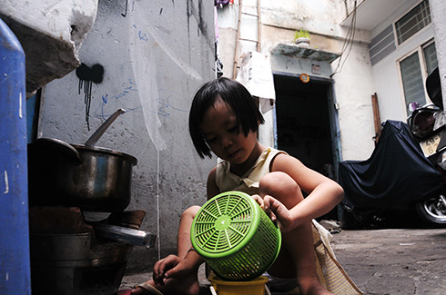 Bé Bảo Ngọc, 5 tuổi con gái út của chị Dung khi không đi học cũng biết phụ giúp mẹ vào bếp. Chỗ nấu ăn là con đường hẻm dân đi lại qua trước cửa nhà