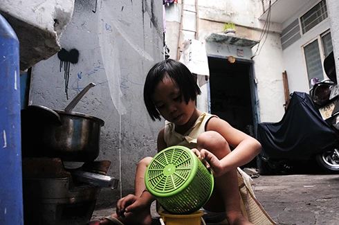 Bé Bảo Ngọc, 5 tuổi con gái út của chị Dung khi không đi học cũng biết phụ giúp mẹ vào bếp. Chỗ nấu ăn là con đường hẻm dân đi lại qua trước cửa nhà