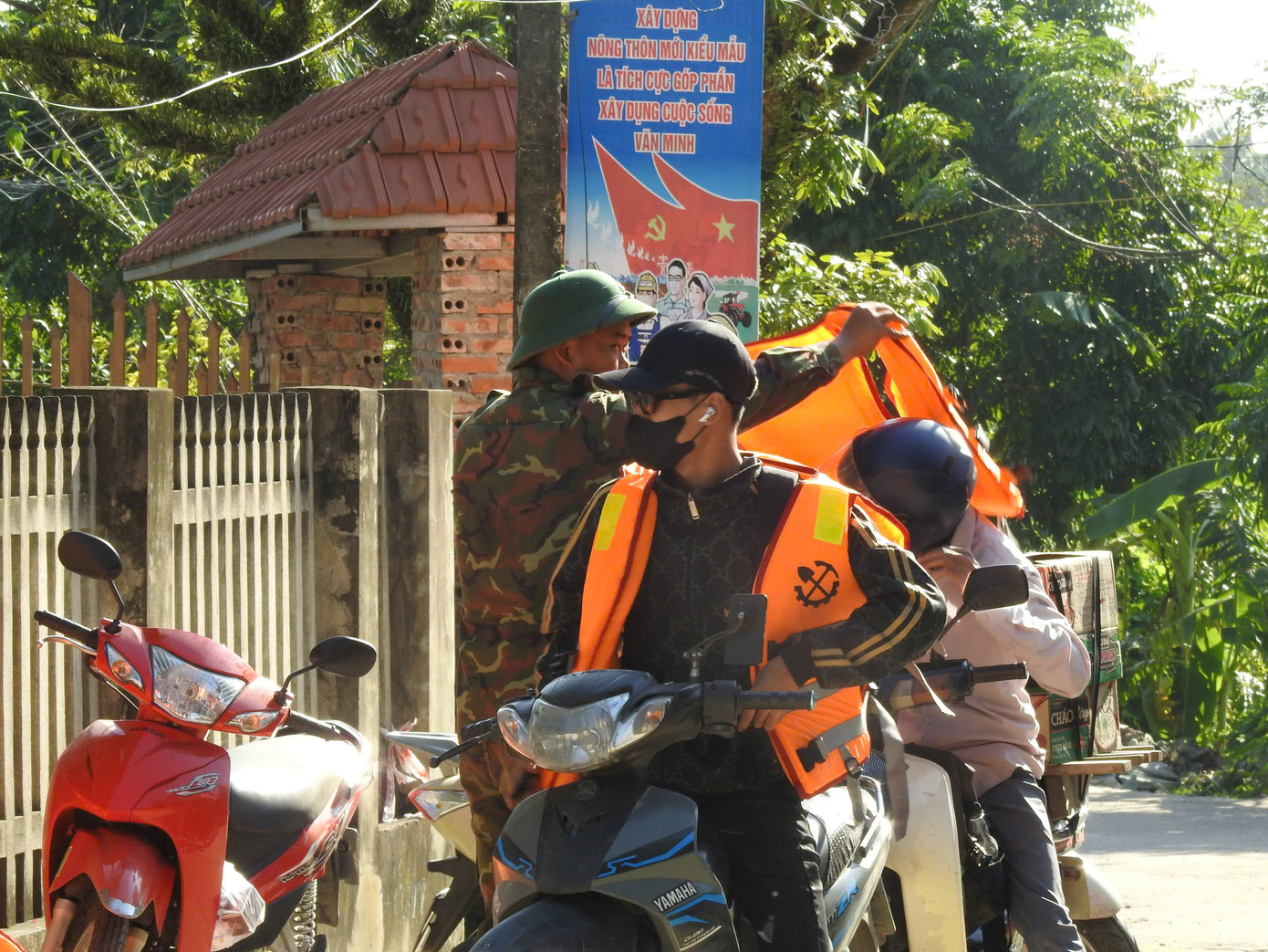 Lực lượng quân đội hướng dẫn người dân mặc áo phao khi tham gia lưu thông qua phà, đảm bảo an toàn và đúng cách.