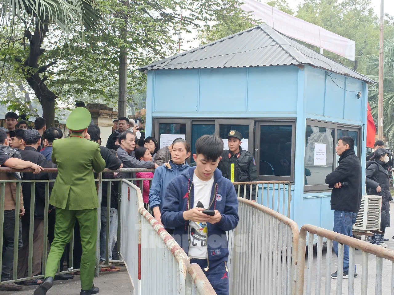 Lực lượng an ninh hướng dẫn người dân đi theo lối được rào vào mua vé.