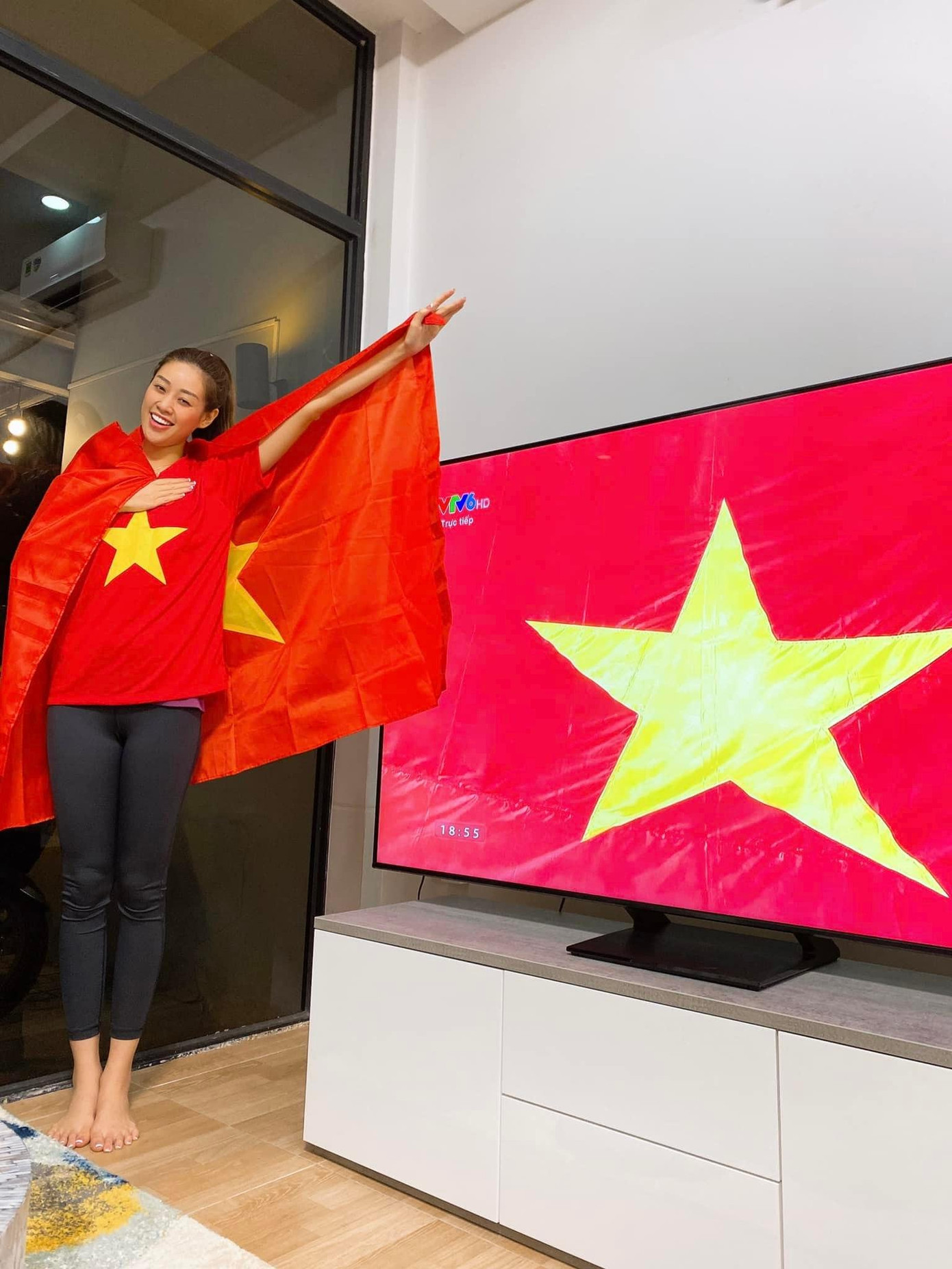 Không có điều kiện trực tiếp ra sân Mỹ Đình, Hoa hậu Khánh Vân mặc áo cờ đỏ sao vàng để cổ vũ tinh thần các cầu thủ khi theo dõi qua truyền hình.