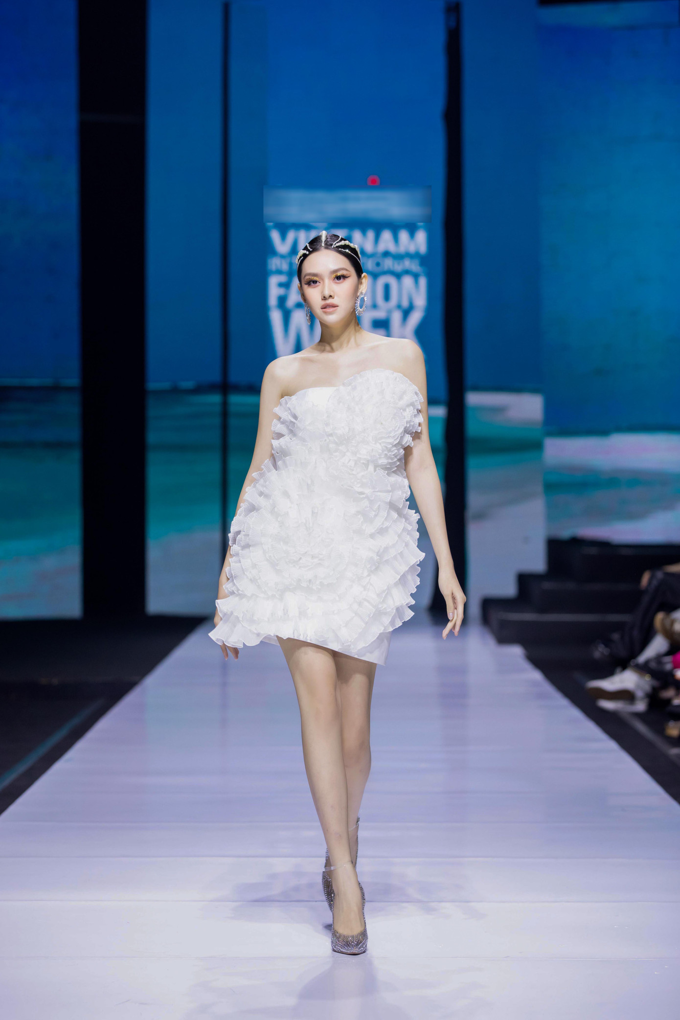 Cô diện bộ váy cúp ngực màu trắng có kiểu dáng khá đơn giản, khoe vai trần mong manh.