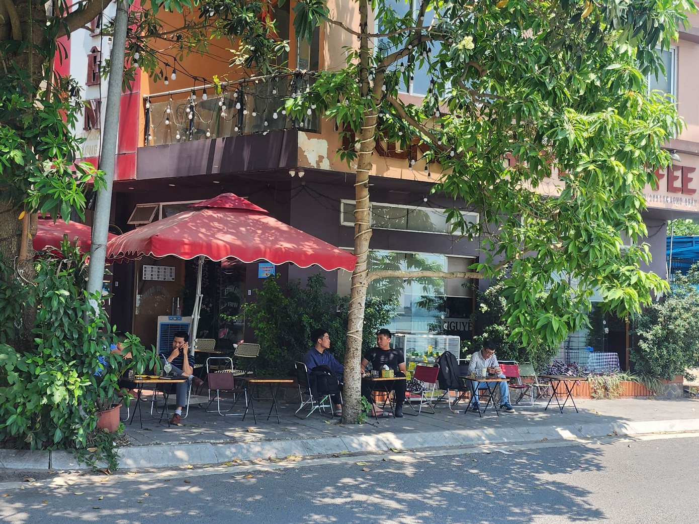 Quán cà phê trên đường Lạc Long Quân chiếm dụng vỉa hè, bày bàn ghế cho khách ngồi.