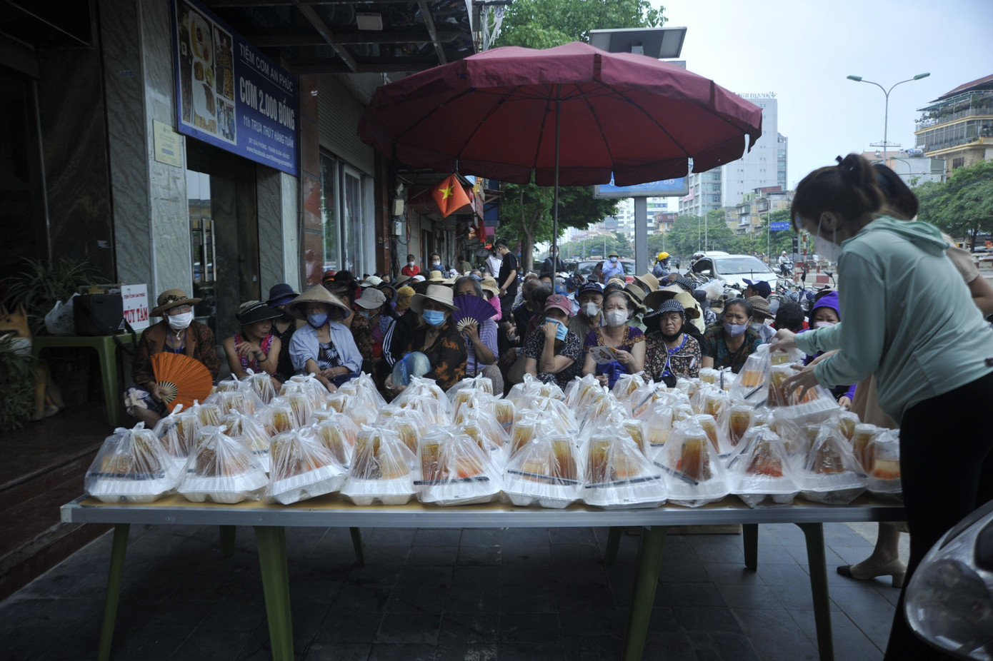 Người dân có hoàn cảnh khó khăn ngồi ngay ngắn chờ đến lượt nhận cơm